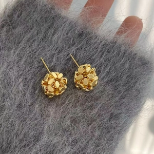 Detail shot of golden textured spherical stud earrings with polished sequin accents