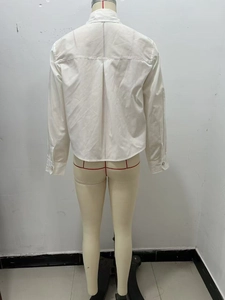 Dettaglio posteriore di camicia in popeline bianco con eleganti bottoni gioiello