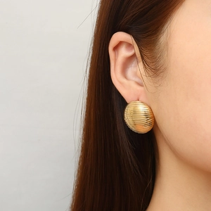 Fashionable hollow round gold earrings with striped texture worn by a model