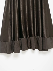 Détail de l'ourlet d'une jupe midi en satin bronze avec tissu brillant et bord volanté