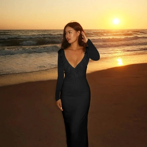 Detail of ruffle trim on black V-neck bodycon long sleeve dress at beach sunset