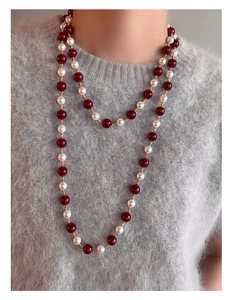 Dettaglio di una collana vintage a doppio strato con perle rosso scuro e perle bianche