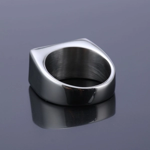 Bague motard homme en acier inoxydable argenté poli sur une surface réfléchissante