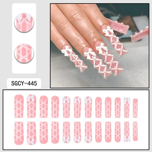 Pink press-on nails with white ribbon crisscross patterns and 3D bow accents