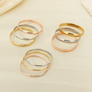 Polished stainless steel stackable bangles in gold, silver, and rose gold on silk fabric