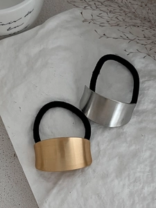 Detailed macro view of gold and silver metallic bow hair ties with black elastic bands