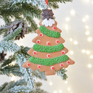 Gingerbread Christmas tree ornament with festive red and green details on a snowy branch