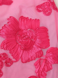 Macro view of pink mesh fabric with detailed ribbon embroidery flowers on the dress