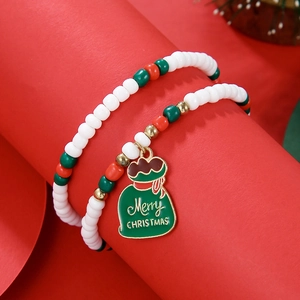 Detailed view of Christmas beaded bracelet with green gift charm on red cylinder