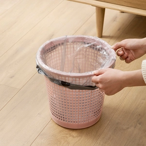 Modern pink hollow plastic waste bin with black liner on a light wood floor