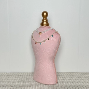 Detailed view of pink floral fabric jewelry bust stand with golden orb top ornament