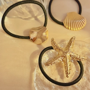 Three-piece gold metal hair ties set featuring starfish, seashell, and round charms