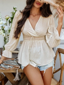 Détail du chemisier beige à col en V avec dentelle à la taille et poignets volantés