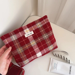 Détail macro d'une trousse de maquillage en tweed à carreaux rouges avec étiquette tissée