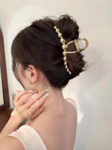 Rear view of gold beaded claw clip holding hair in place on an elegant model
