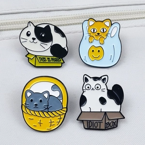 Set of four cute cartoon cat enamel pins in colorful boxes on canvas texture