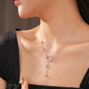 Close-up of silver zircon star and moon Y-shaped necklace on female collarbone