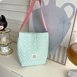 Detail of mint green quilted tote with heart patterns and pink straps in a modern setting
