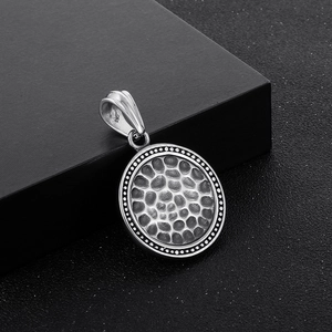 Macro shot of silver hammer texture round pendant with dot edges on black box