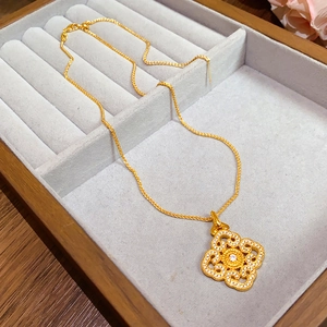 Close-up of a gold hollow floral pendant with crystals in a grey velvet jewelry box