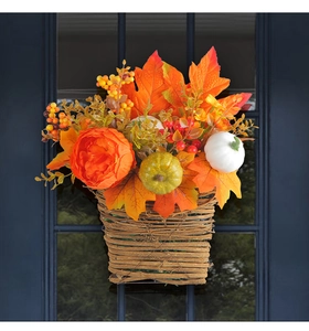 Harvest pumpkin flower basket with autumn maple leaves hanging on a blue glass door