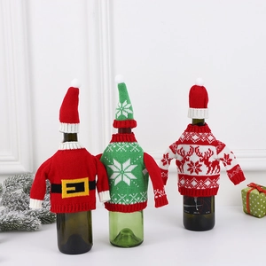 Three festive Christmas knitted wine bottle covers with mini hats on a holiday background