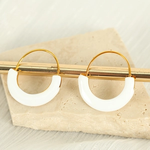 Minimalist gold and white enamel D-shaped hoop earrings hanging on a display stand