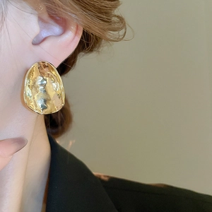 Close-up of irregular textured gold earrings on a model showing modern minimalist style
