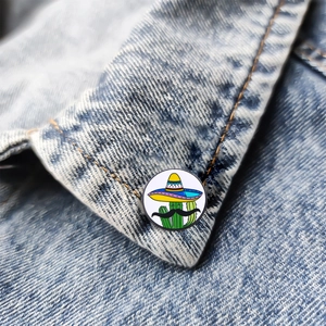 Cartoon cactus enamel pin with sombrero and mustache on a blue denim jacket collar