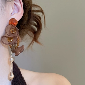 Macro shot of brown organza floral earrings with long gold chains on a model