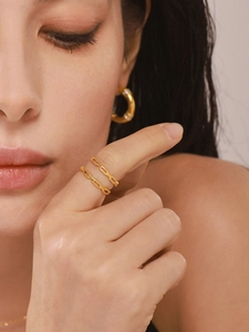 Close-up of dual gold-plated stainless steel rings with minimalist chain texture design