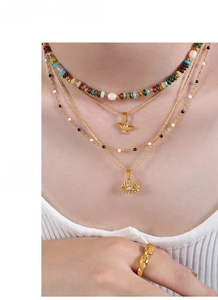 Layered titanium steel necklaces featuring evil eye and bird pendants on female model