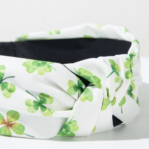 Detail of white fabric headband with green clover print and elegant top knot design