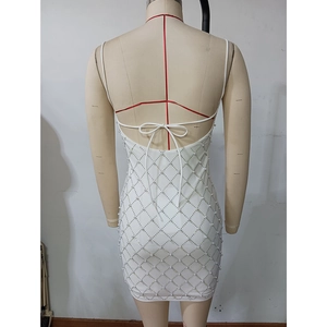 Détail de la robe courte blanche avec dos en résille perlée et nœud décoratif