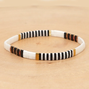 Bohemian Tila bead bracelet with black white and gold tiles on a wooden display