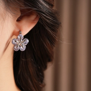 Gros plan sur des boucles d'oreilles fleur en argent avec zircons portées par un mannequin