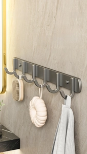 Modern gun grey wall hooks in a bathroom showing a towel, bath brush, and loofah