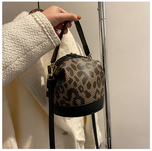 Detail shot of leopard print bucket bag with black leather trim and gold metal hardware