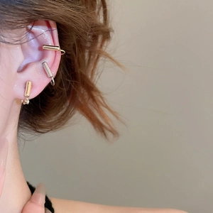 Close-up of gold and silver geometric ear cuff set worn on female model's ear