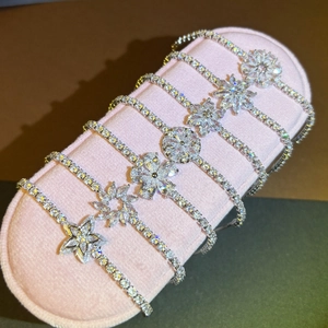 Détail de bracelets fleurs en argent avec zircons cubiques sur un coussin en velours rose