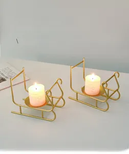 Detail of golden sleigh-shaped candle holders with white pillar candles for table decor