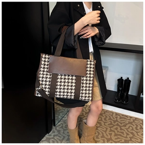 Detail of vintage houndstooth tote bag with brown leather accents shown on a model