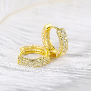 Close-up of gold-plated heart earrings with sparkling pavé rhinestones on white feathers