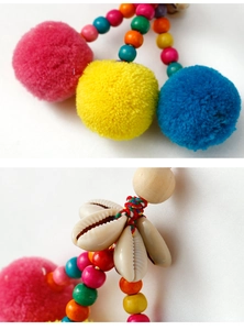 Detail of bohemian bag charm with colorful pompoms, natural shells, and wooden beads