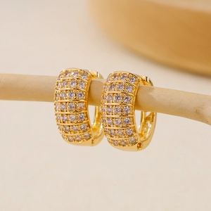 Chunky gold hoop earrings with multi-row pave cubic zirconia on a minimalist wood stand