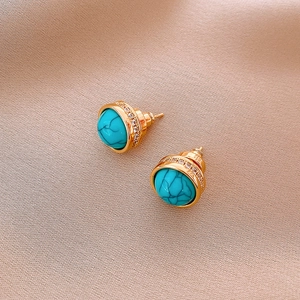 Detailed macro of gold plated earrings featuring turquoise stone and white zircon accents
