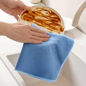 Panno in microfibra blu che pulisce un piatto sporco in un ambiente cucina