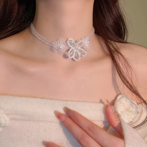 Detailed macro view of white floral choker with lace petals and delicate crystal beads