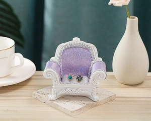 Macro shot of miniature lavender velvet sofa jewelry stand displaying vintage stud earrings