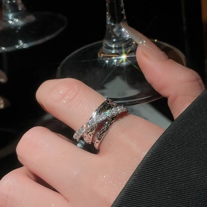 Macro shot of silver crisscross ring with pavé zircons sparkling against dark background